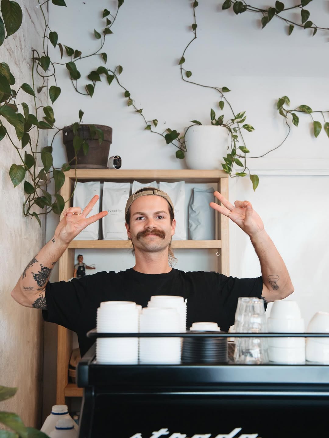 Two peace signs in front of iv coffee beans shelf